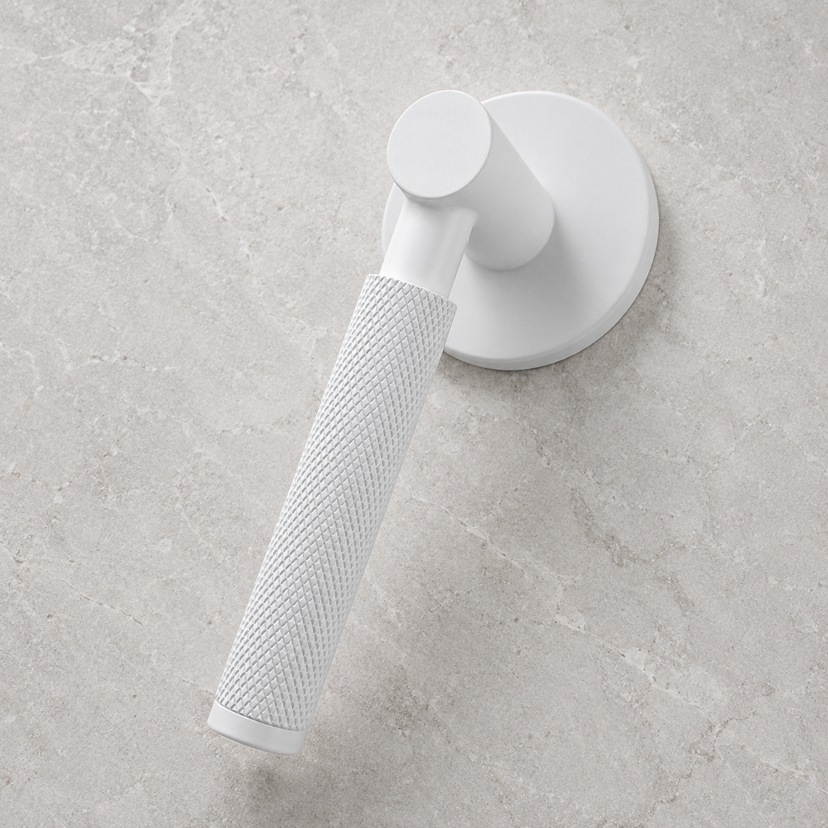 A modern white wall-mounted shower hand shower with a textured grip and circular wall plate, shown against a light gray stone-look tiled background.